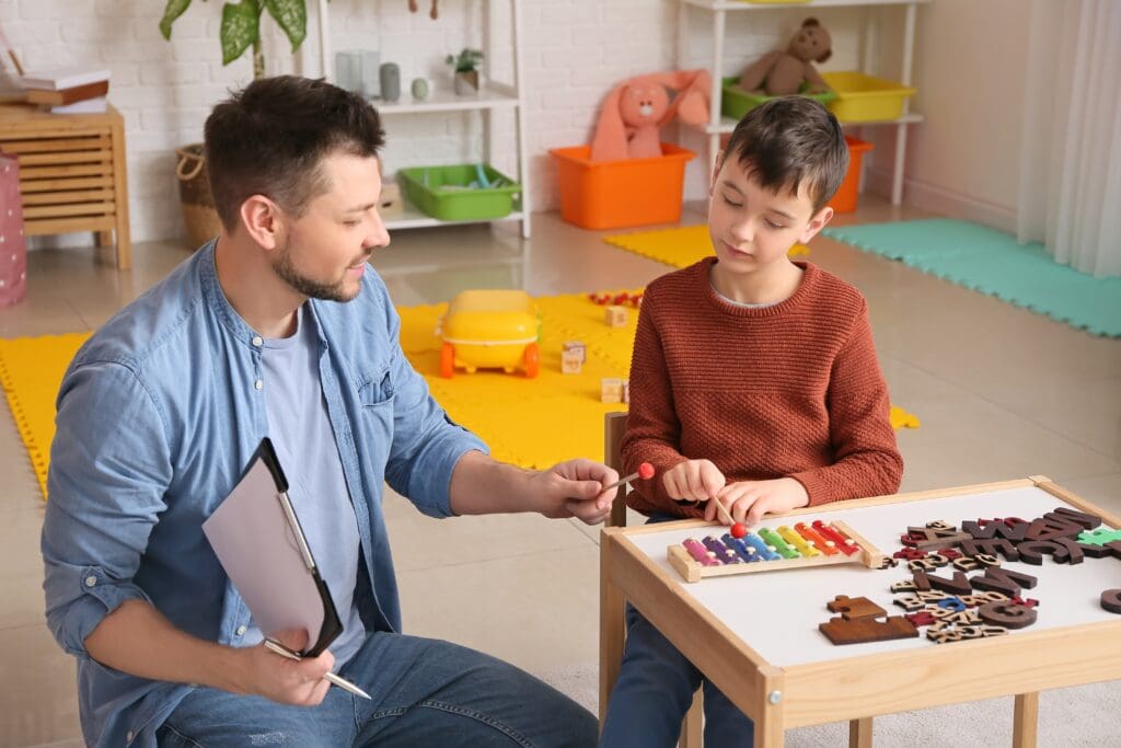 Male,Psychologist,Working,With,Little,Boy,In,Office.,Autism,Concept